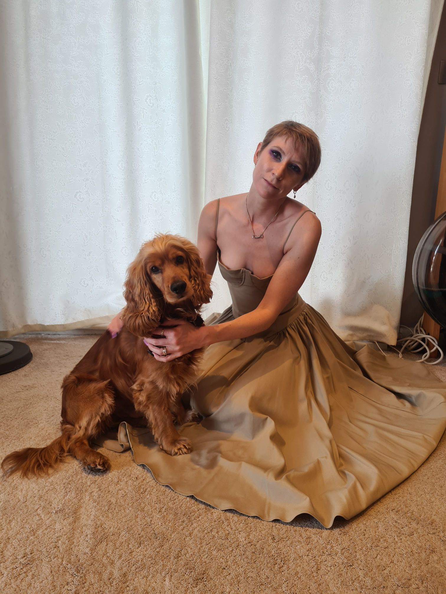 Women posing with a sage green, full length dress with a dog.